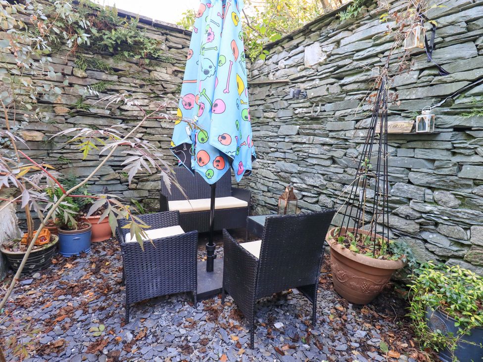 A garden with a table and chairs under an umbrella at Buttonhole Cottage in Ambleside