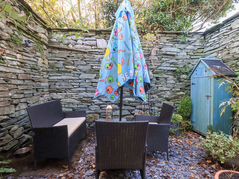 A garden seating area with a colorful umbrella at Buttonhole Cottage Ambleside