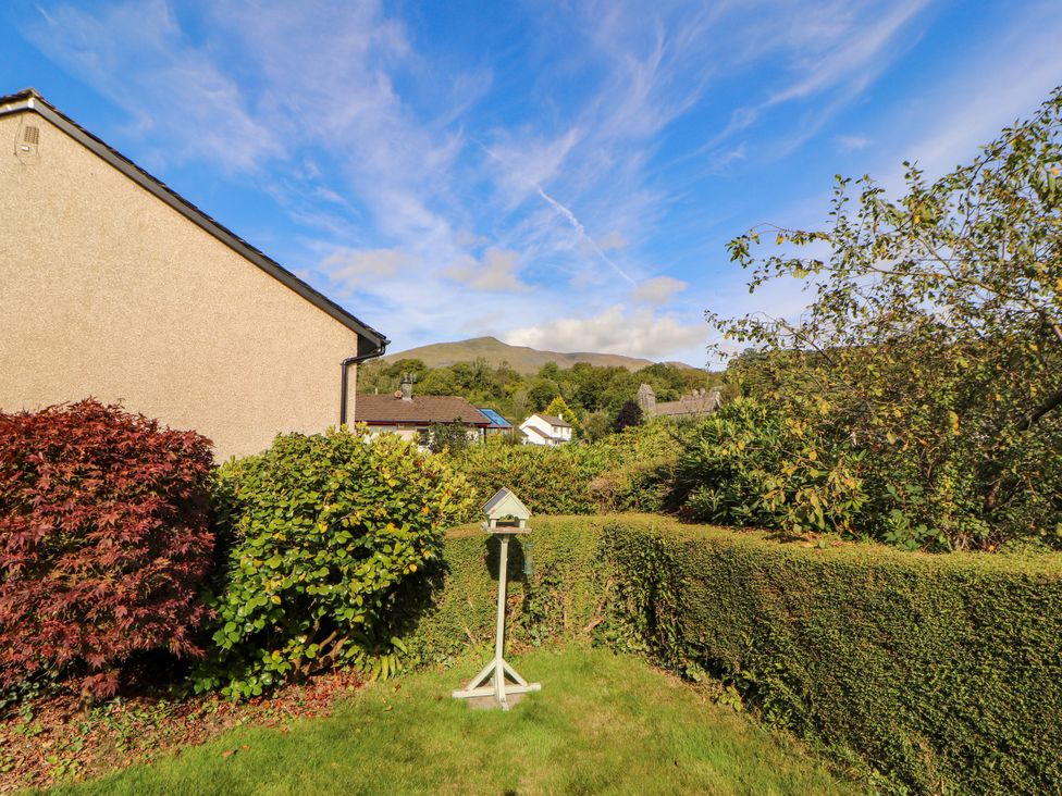 A garden with hedges and a bird feeder at Sunbeam Cottage Coniston