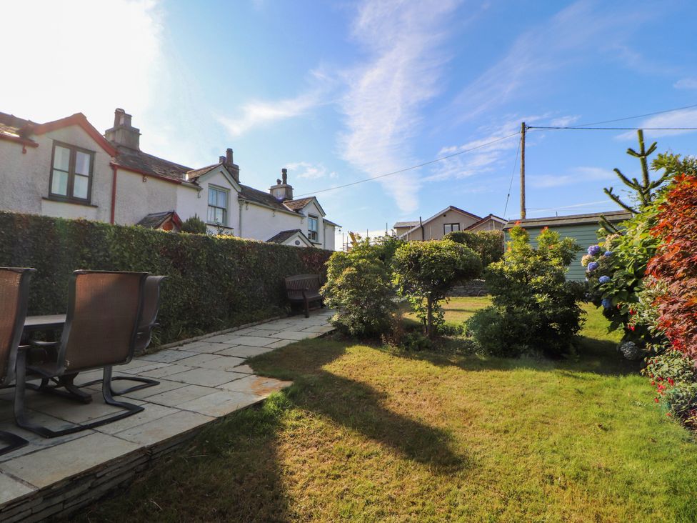 A garden with a table and chairs and houses in the background at Sunbeam Cottage Coniston