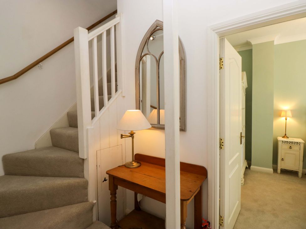 A hallway with a staircase and a console table at Chapel How in Ambleside