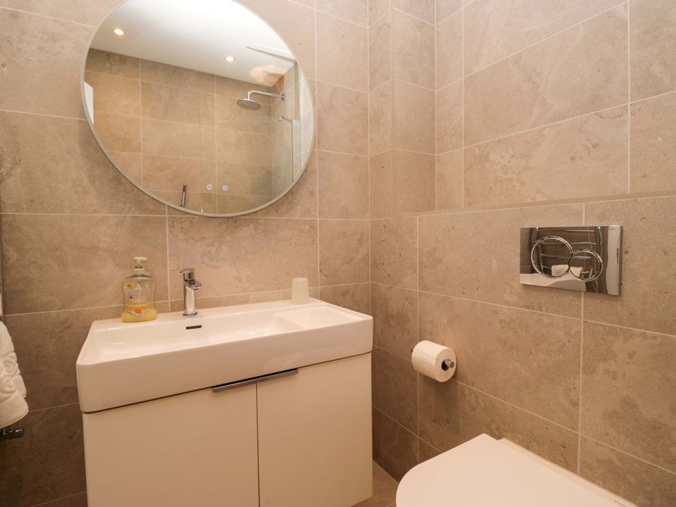 A bathroom with a sink, toilet, and mirror at Chapel How in Ambleside