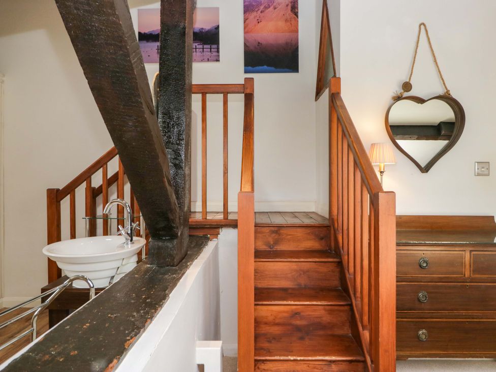 A staircase leading to a hallway with a sink and wooden furniture at Chapel How in Ambleside