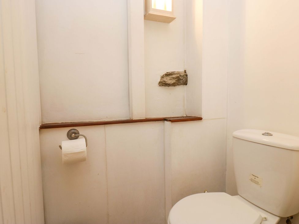 A bathroom with a toilet and wooden shelf at Chapel How in Ambleside