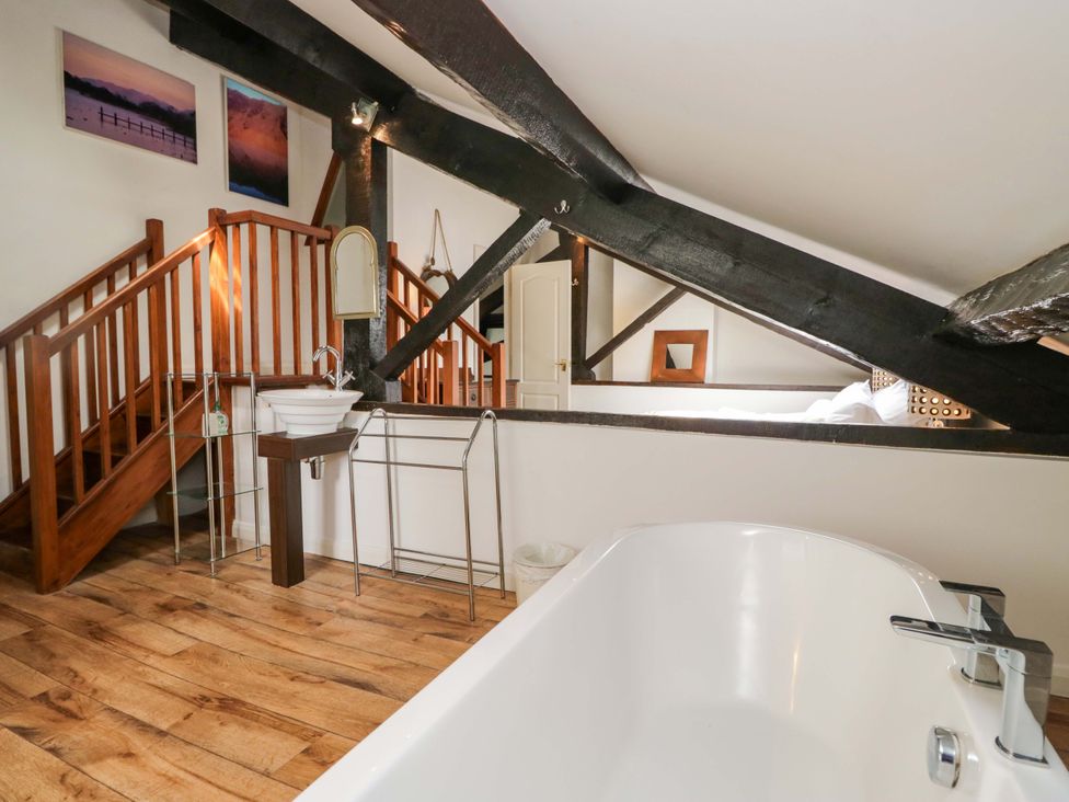 A bathroom with a bathtub and staircase at Chapel How in Ambleside