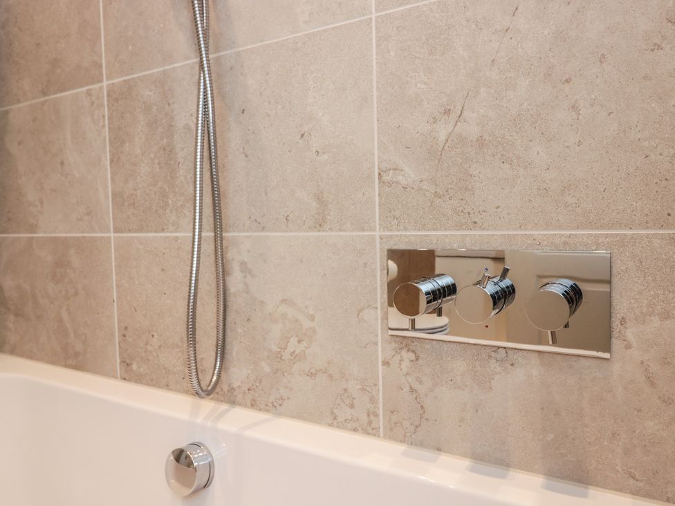 A bathtub with a showerhead and faucet controls at Chapel How Ambleside
