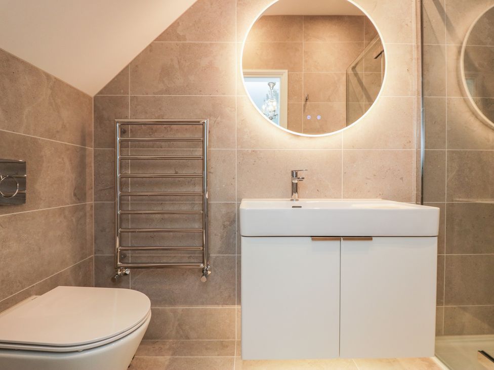 A bathroom with a sink, toilet, mirror and towel rack at Chapel How in Ambleside