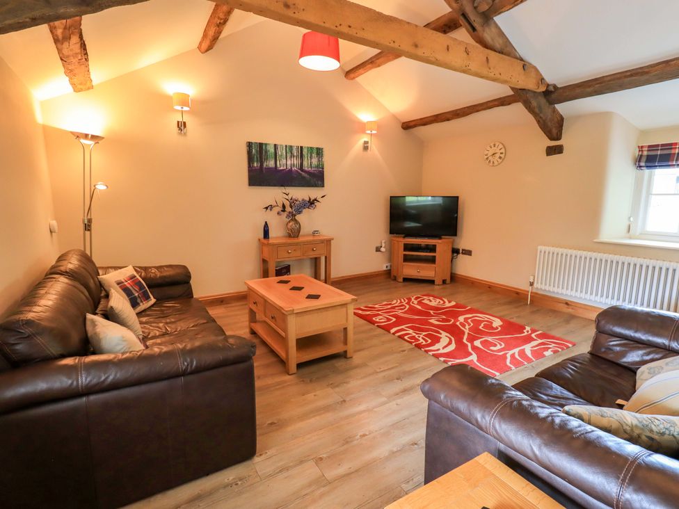 A living room with a sofa, coffee table and television at Abbots Reading Mews 1 in Grizedale