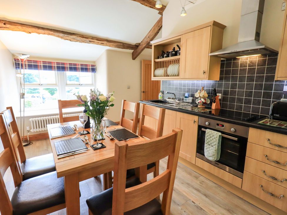 A kitchen with a dining table and wooden chairs at Abbots Reading Mews 1 in Grizedale
