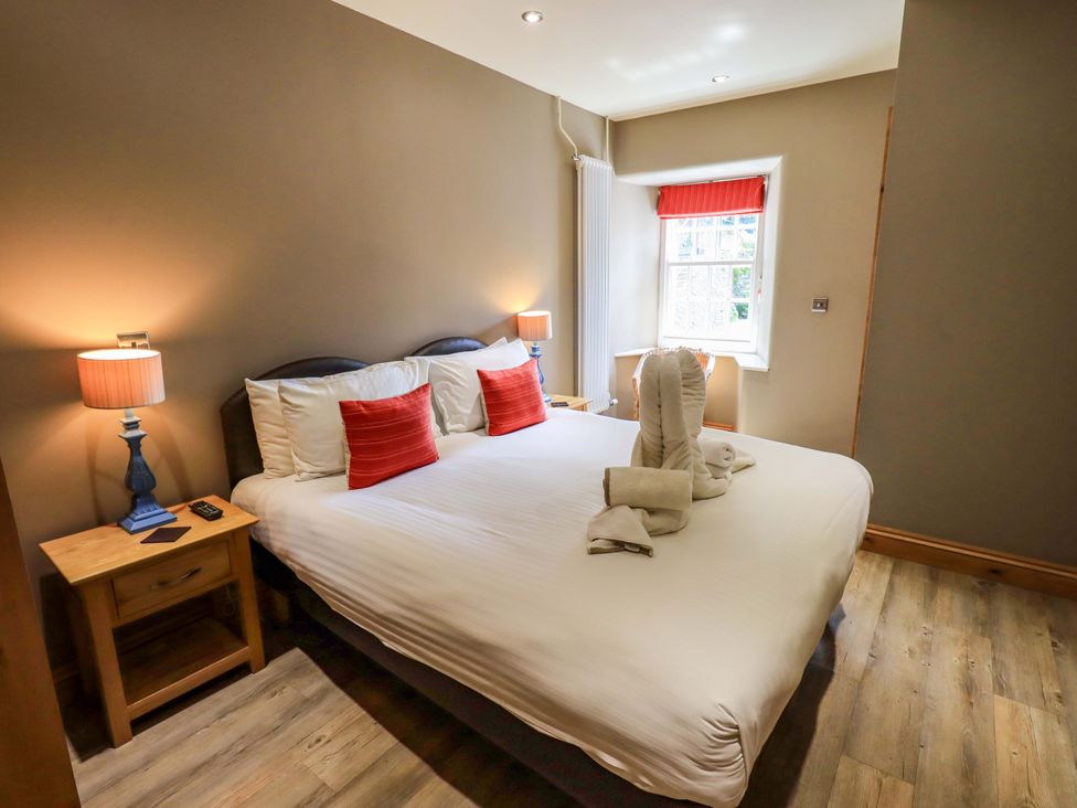 A bedroom with a bed, lamps, and a window at Abbots Reading Mews 1 in Grizedale