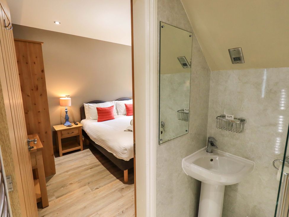 A bedroom with a bed and nightstand beside a bathroom at Abbots Reading Mews 1 in Grizedale