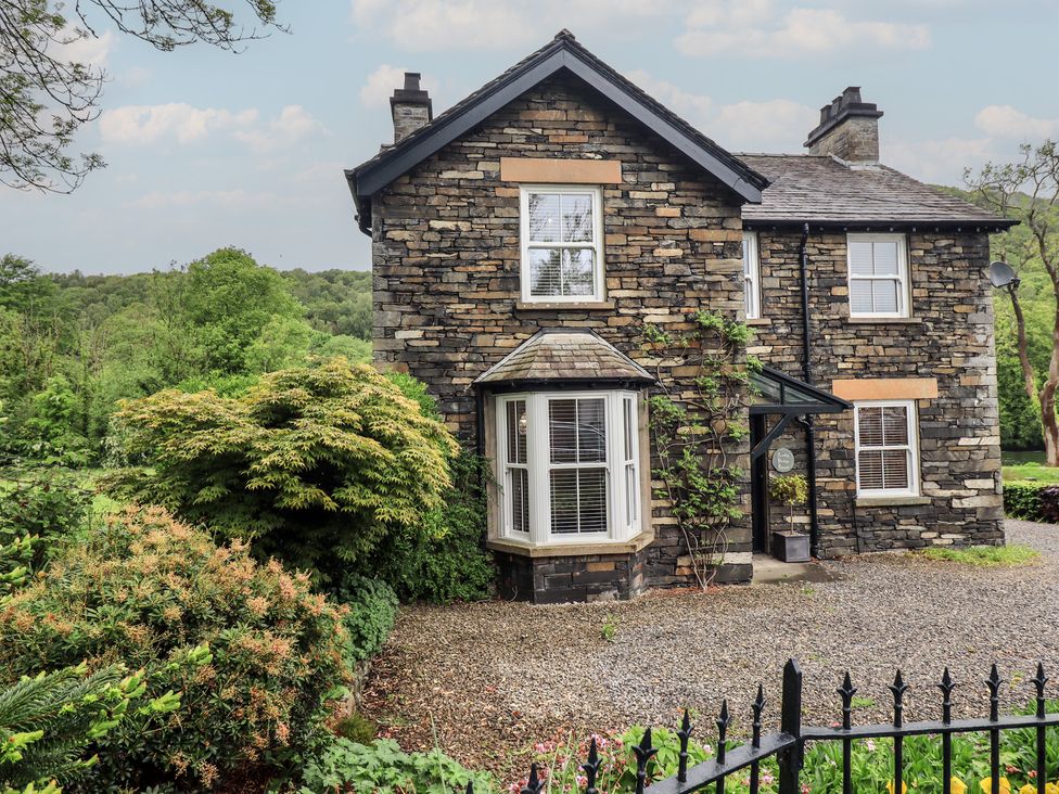 A house with a stone exterior and windows at Newby Bridge House in Newby Bridge