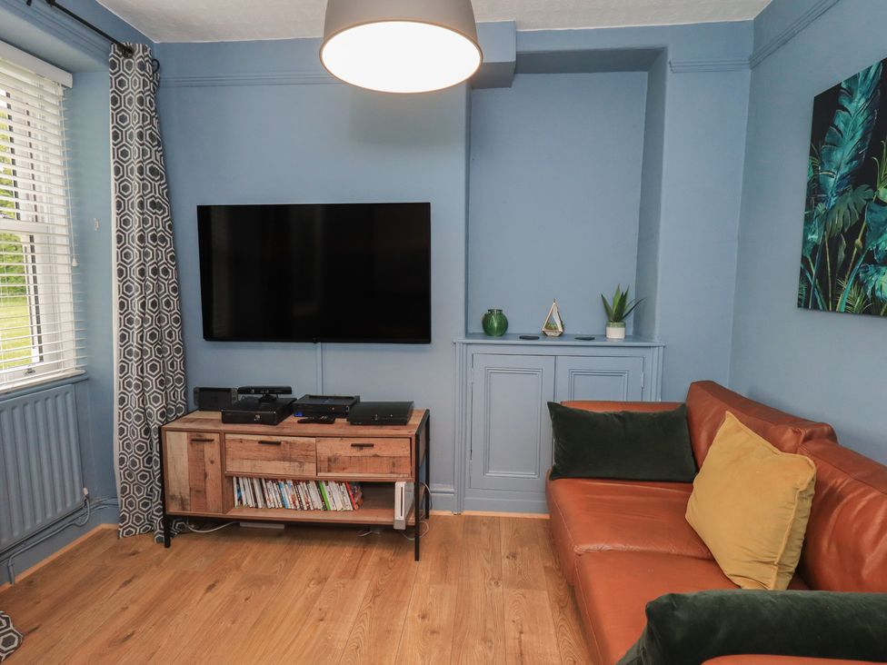 A living room with a television and sofa at Newby Bridge House in Newby Bridge