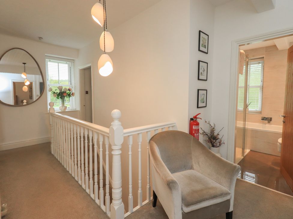 A hallway with a staircase and armchair at Newby Bridge House, Newby Bridge
