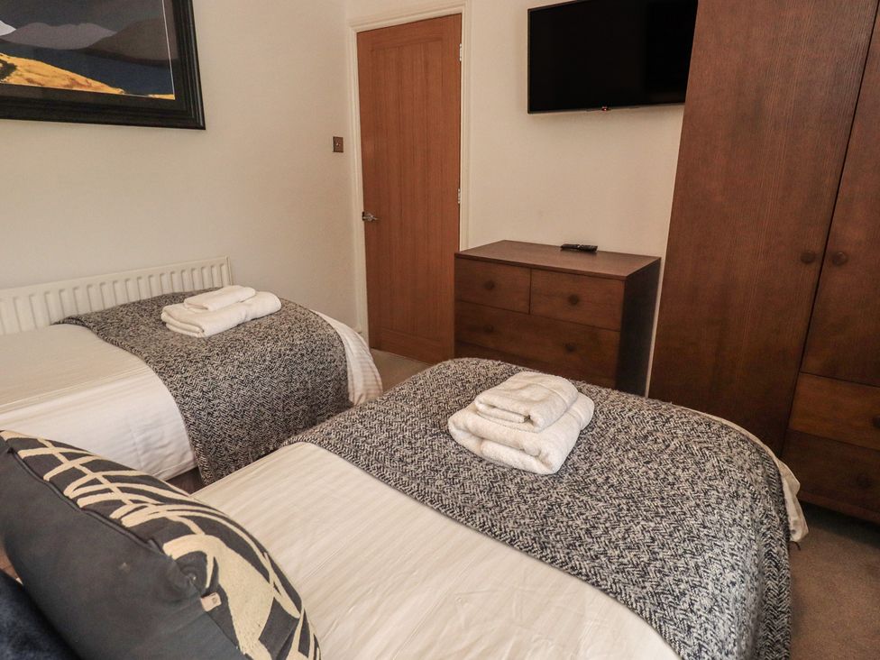 A bedroom with two beds and a television at Newby Bridge House in Newby Bridge