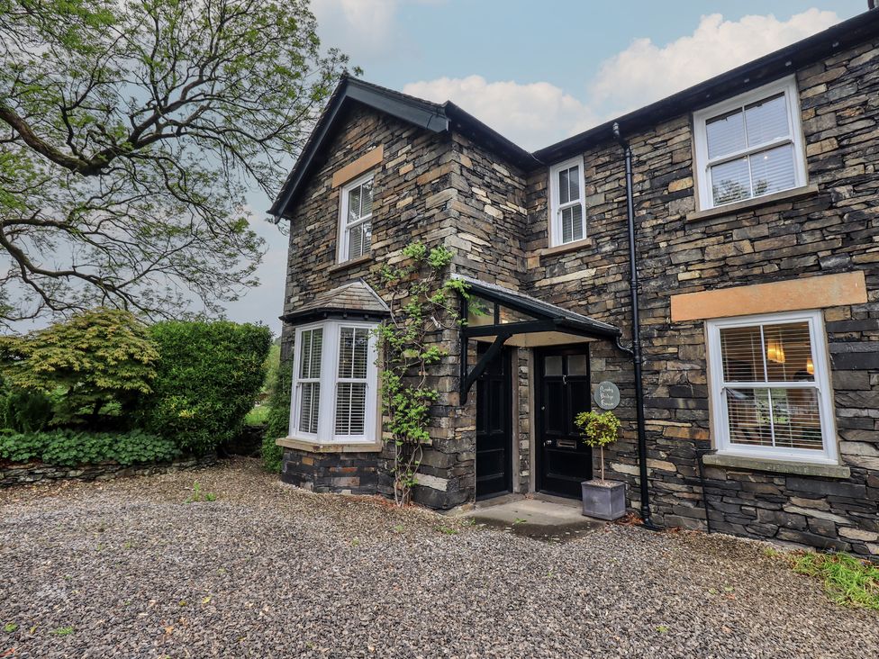 A stone building with an entrance and plants near the door at Newby Bridge House in Newby Bridge
