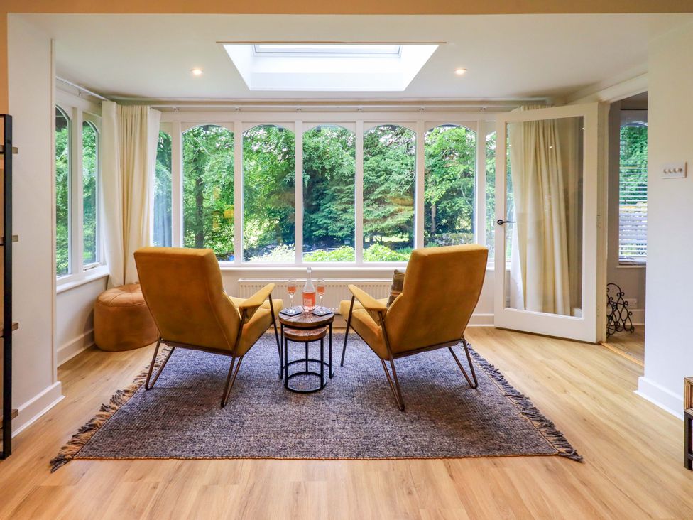 A conservatory with two armchairs and a side table at Underheron in Grasmere