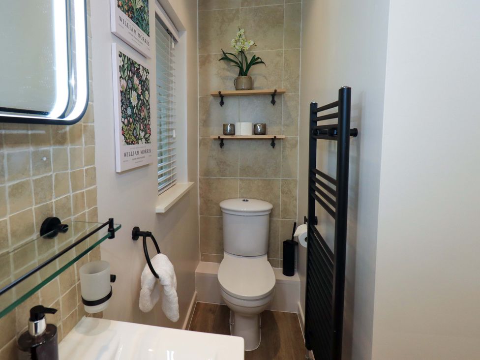 A bathroom with a toilet, sink, and shelves at Underheron in Grasmere