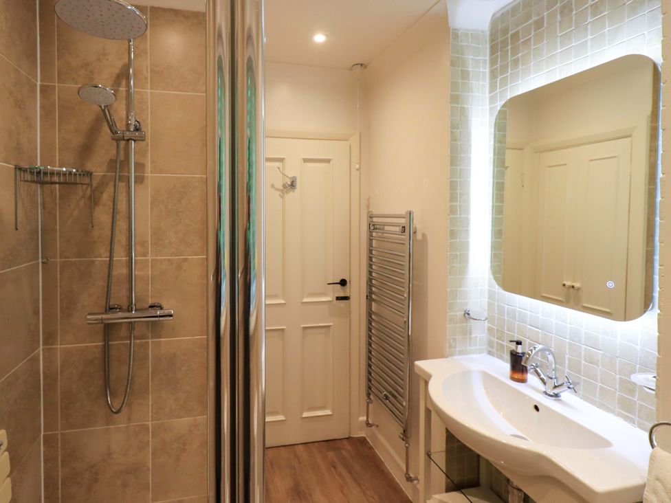 A bathroom with a shower, sink, and towel radiator at Underheron in Grasmere
