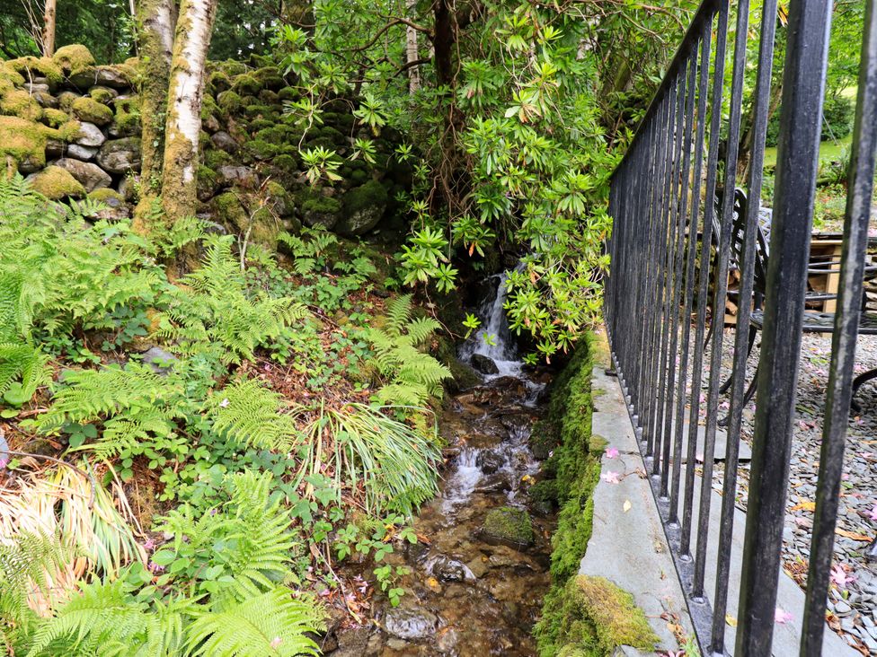 A stream with ferns and rocks near a fence at Underheron in Grasmere