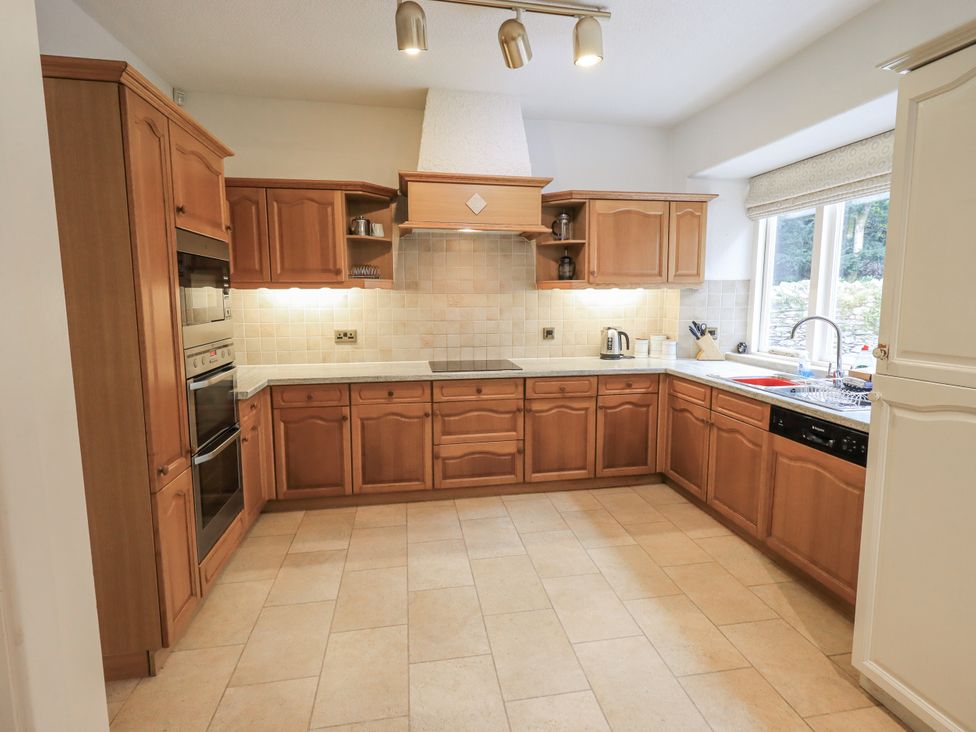 A kitchen with wooden cabinets and appliances at Miyanli in Bowness