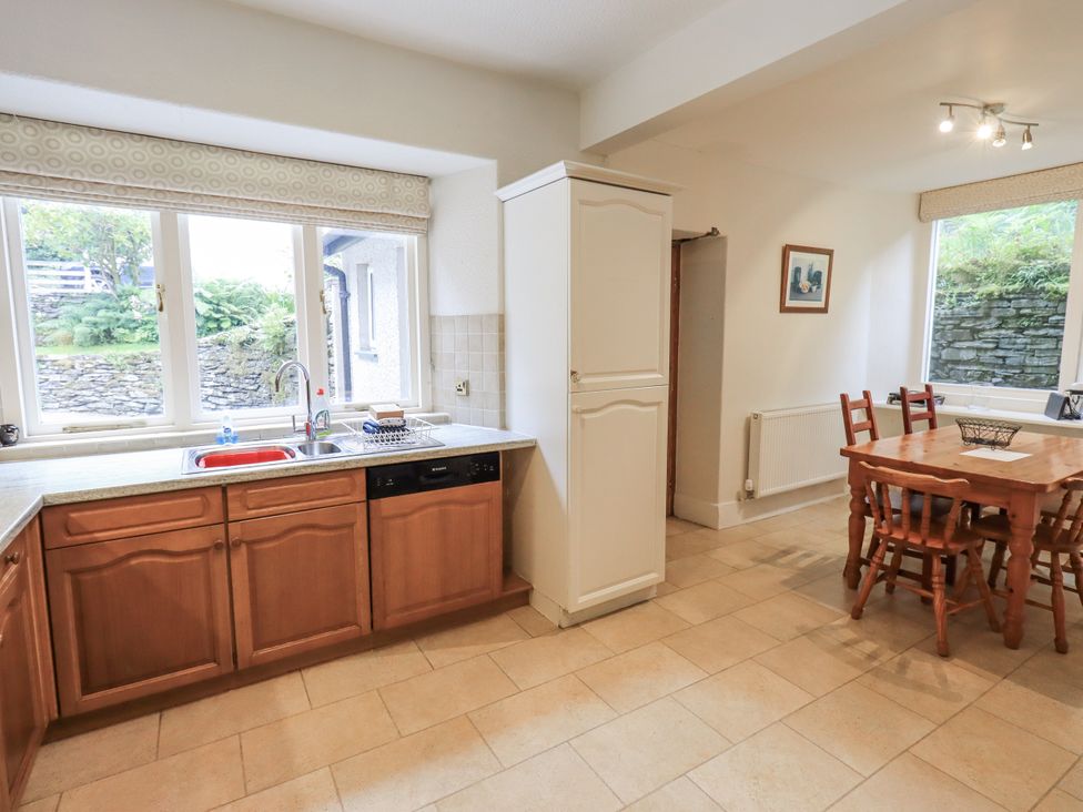 A kitchen with wooden cabinets and a dining table at Miyanli in Bowness