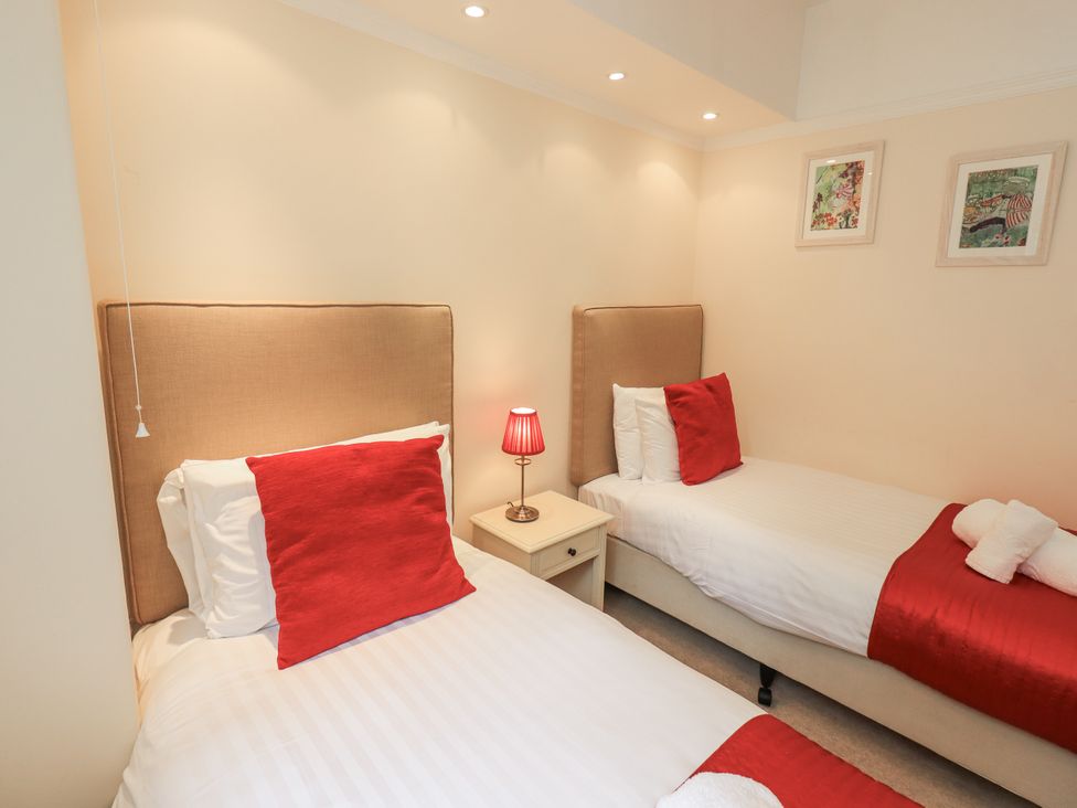 A bedroom with two beds and a lamp on a nightstand at Miyanli in Bowness