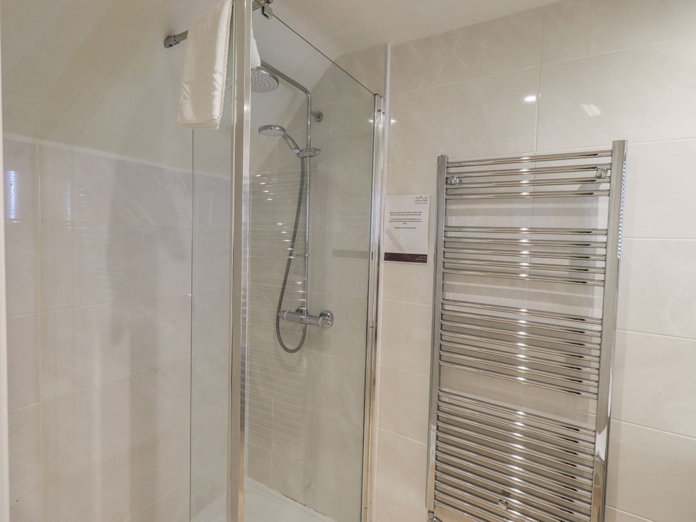 A shower with glass doors and a towel rack at Miyanli in Bowness