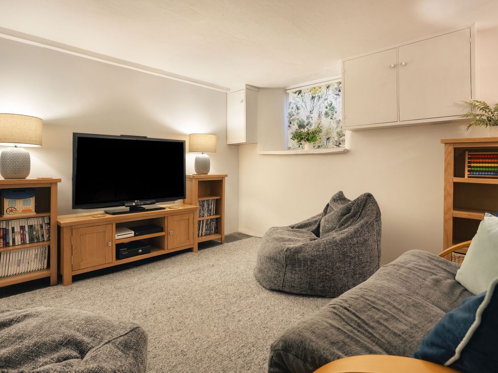 A living room with a television and shelves at Herdwick Cottage Ambleside