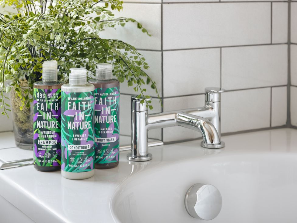 A bathroom with shampoo, conditioner, and body wash at Herdwick Cottage Ambleside