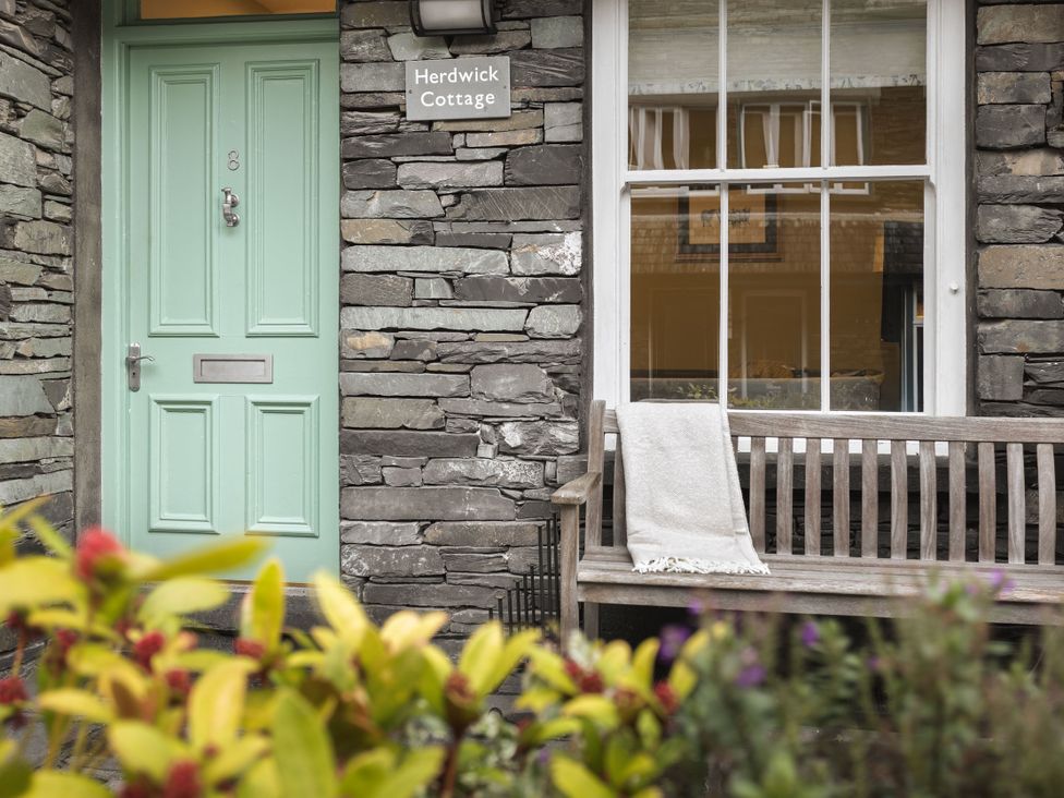 An entrance with a mint green door and wooden bench at Herdwick Cottage Ambleside