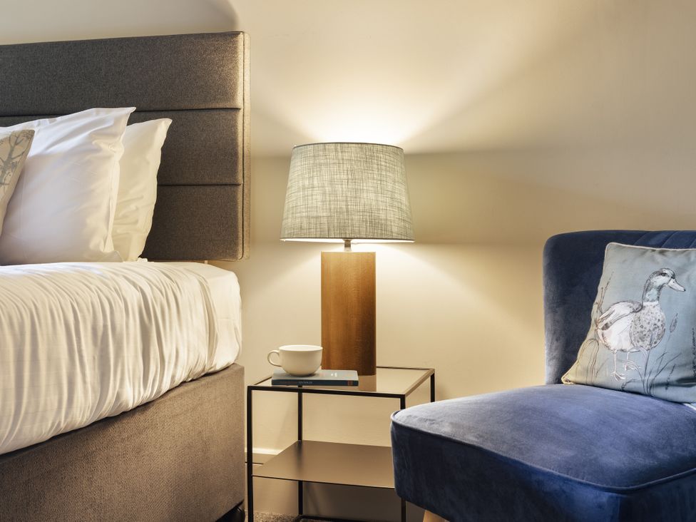 A bedroom with a bed, lamp, and armchair at Take Five in Ambleside