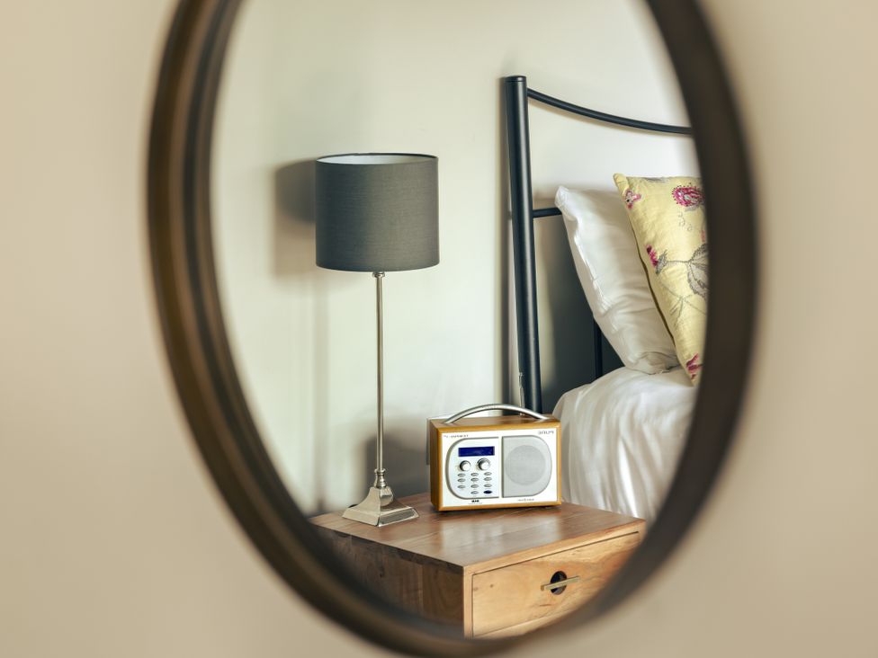 A bedroom with a bed and a lamp reflected in a mirror at Take Five in Ambleside