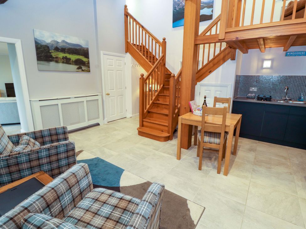 A living room with a staircase and dining area at Cragfell Cottage in Cartmel Fell