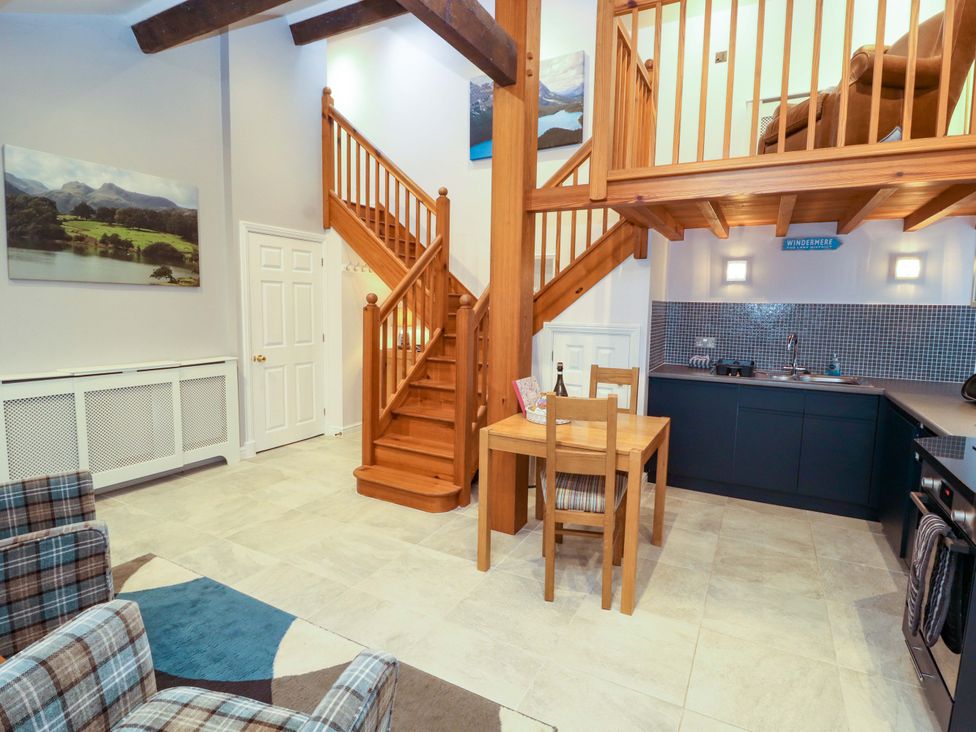 A living room with staircase and kitchen units at Cragfell Cottage in Cartmel Fell