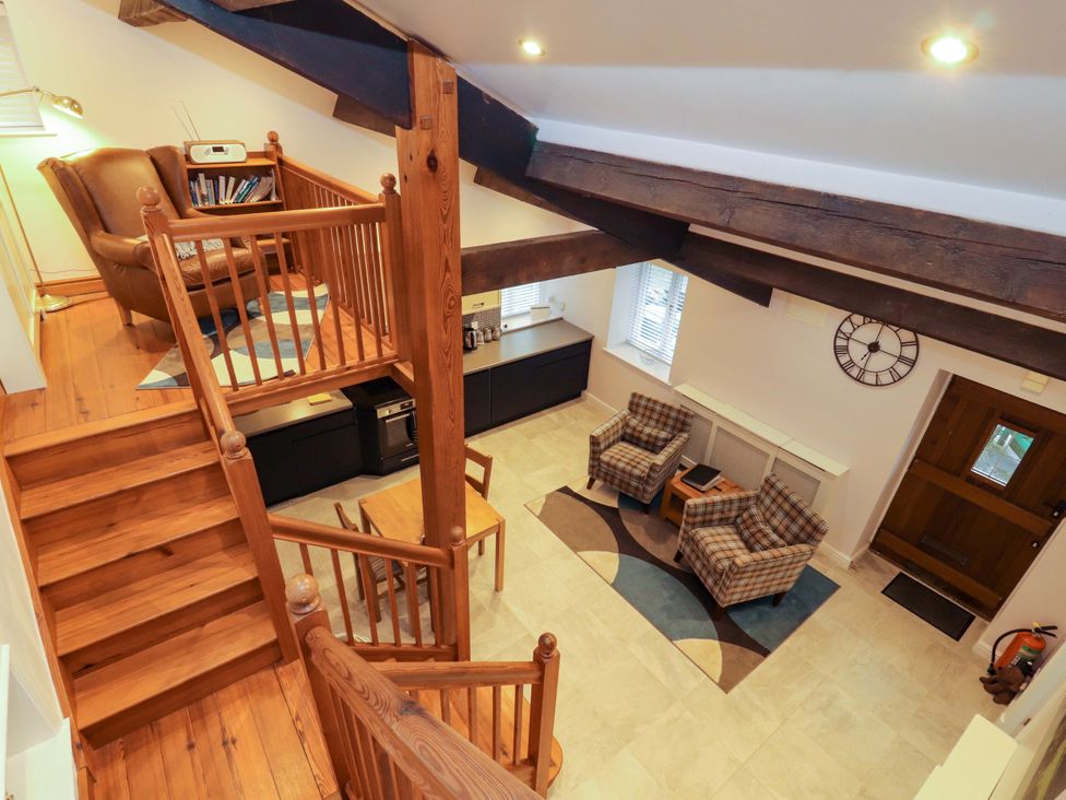 A living room with a staircase and seating area at Cragfell Cottage in Cartmel Fell