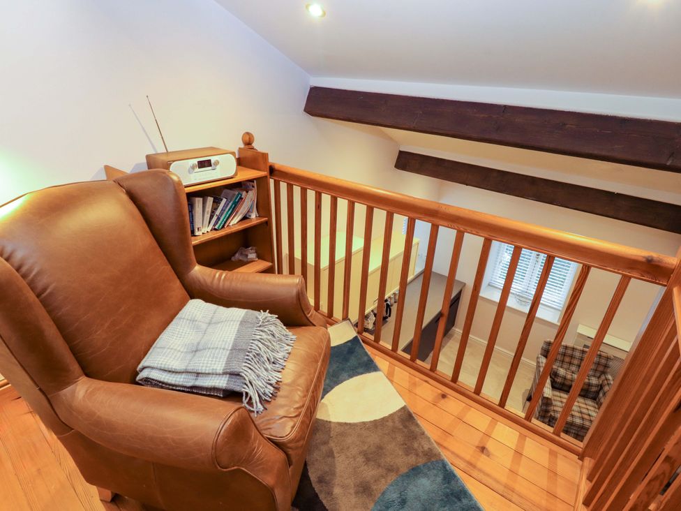 A landing with an armchair and bookshelf at Cragfell Cottage in Cartmel Fell