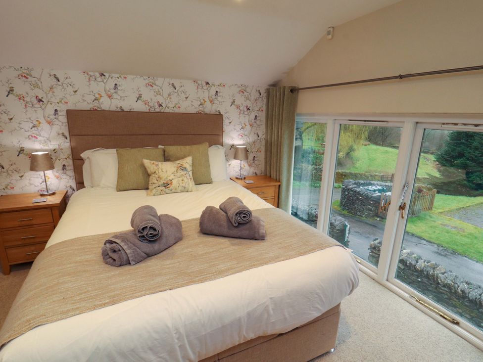 A bedroom with a bed and view of the outside at Cragfell Cottage in Cartmel Fell