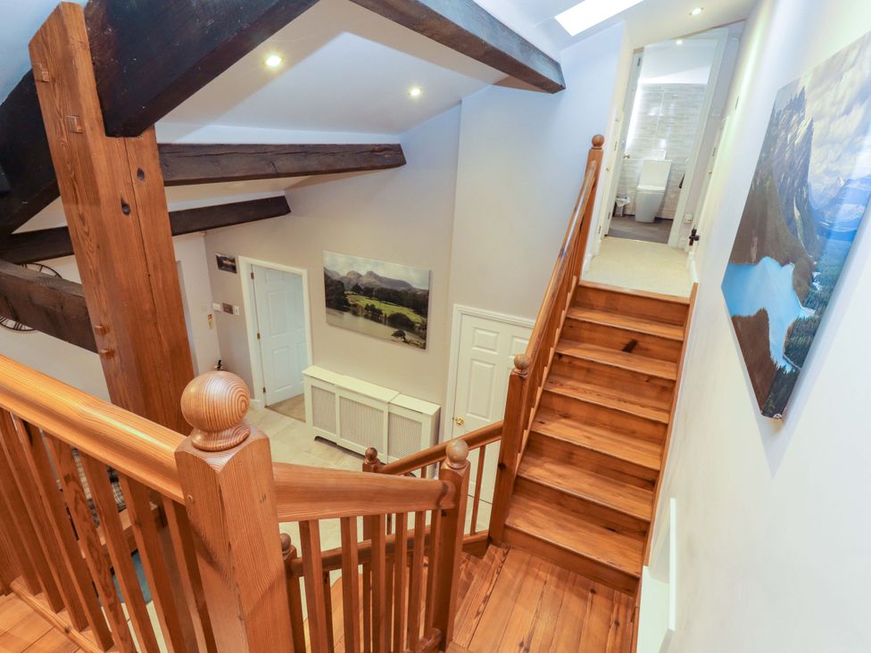 A staircase with wooden railing leading to a hallway at Cragfell Cottage in Cartmel Fell