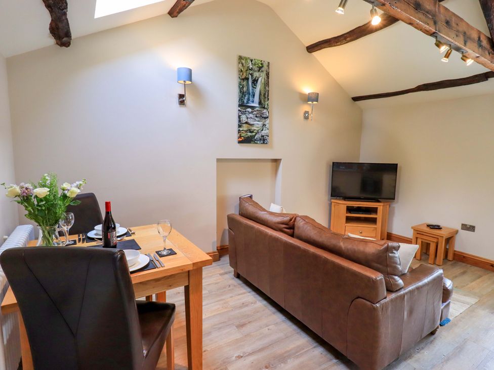 A living room with a sofa and dining area at Abbots Reading Mews 2 in Grizedale