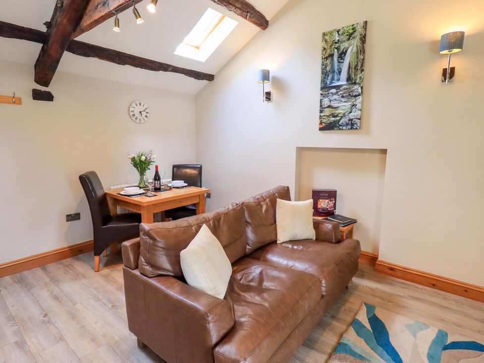 A living room with a sofa and dining area at Abbots Reading Mews 2 in Grizedale