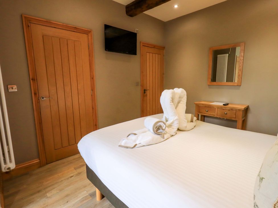 A bedroom with a bed, mirror, and television at Abbots Reading Mews 2 in Grizedale