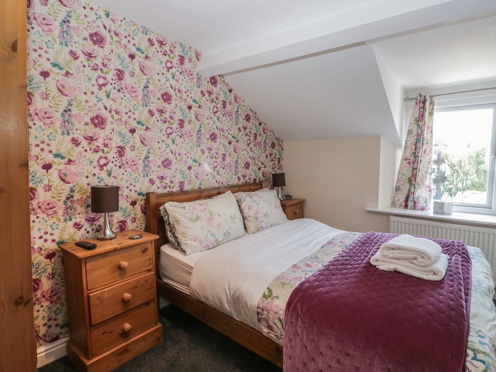 A bedroom with a bed and floral wallpaper at Woodside West in Bowness