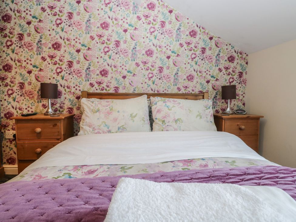 A bedroom with a bed and nightstands at Woodside West in Bowness