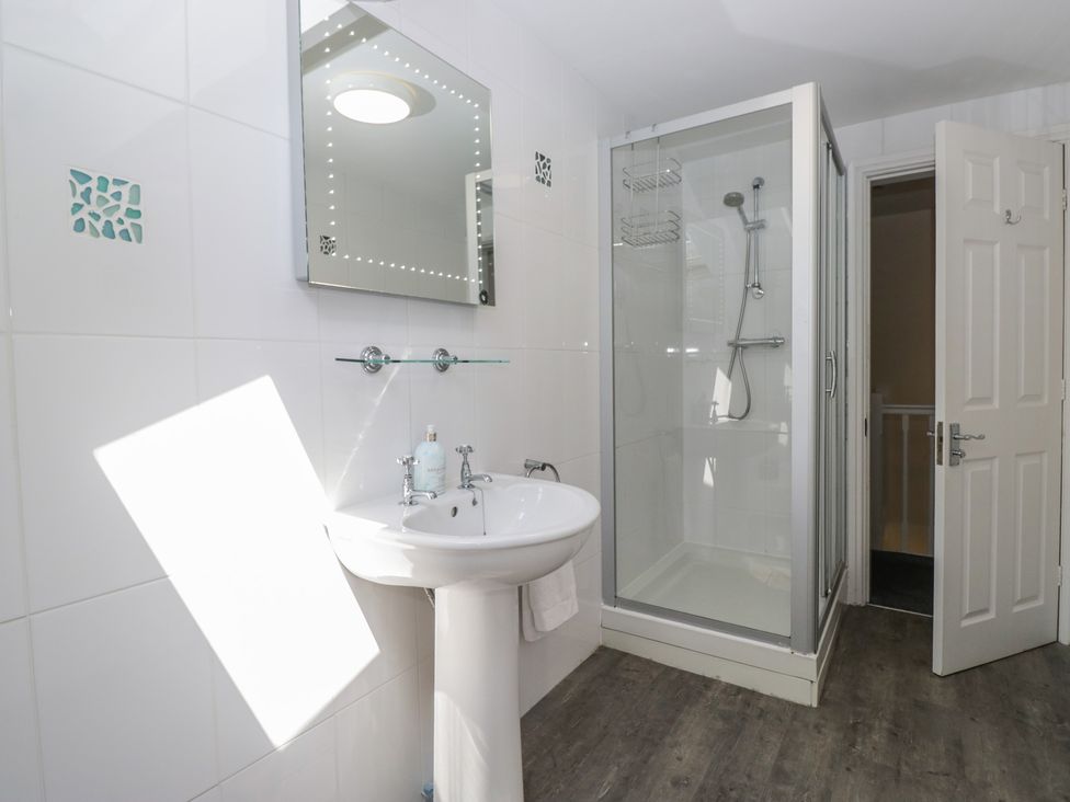 A bathroom with a sink, shower, and mirror at Woodside West in Bowness