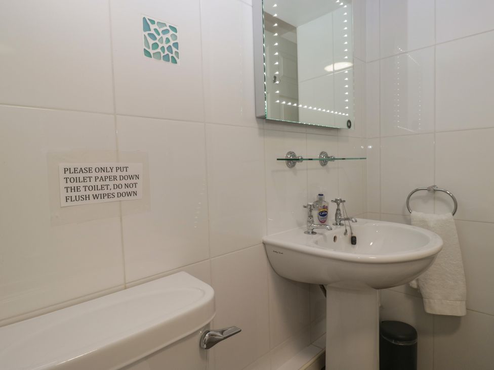 A bathroom with a sink, toilet, and mirror at Woodside West in Bowness