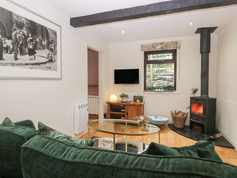 A living room with a wood stove and television at Corner Cottage in Troutbeck