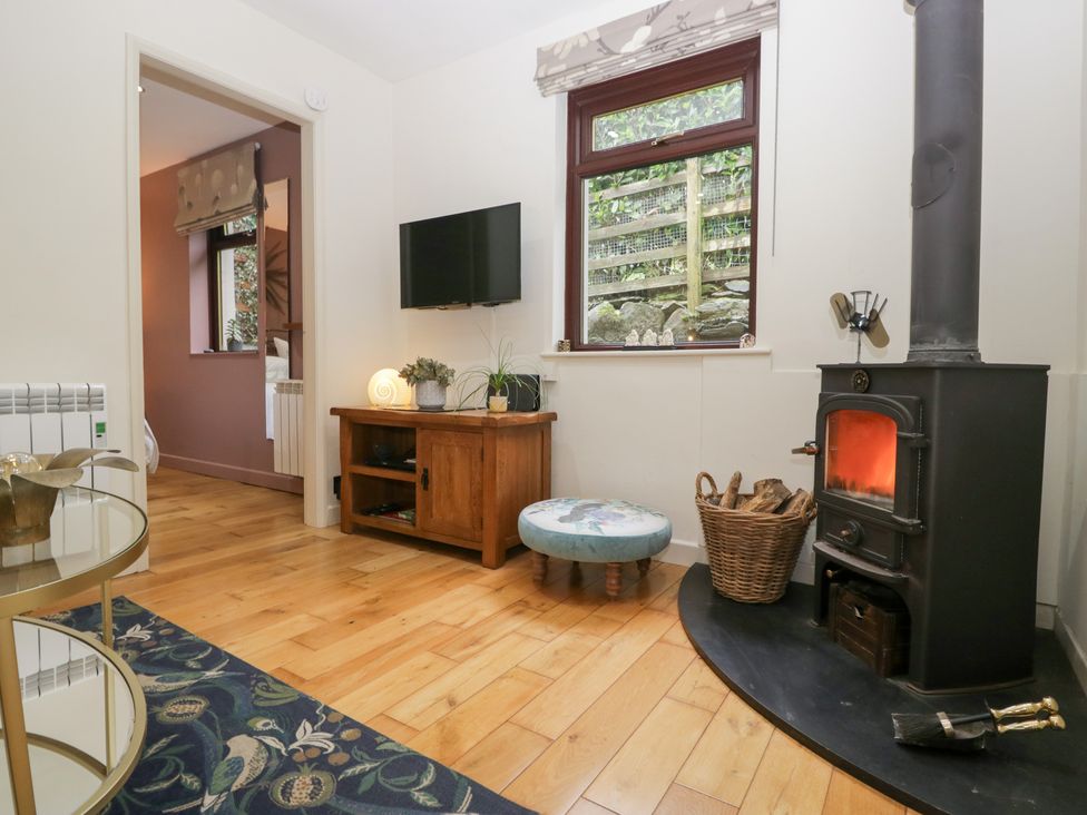 A snug with a wood stove and television at Corner Cottage in Troutbeck