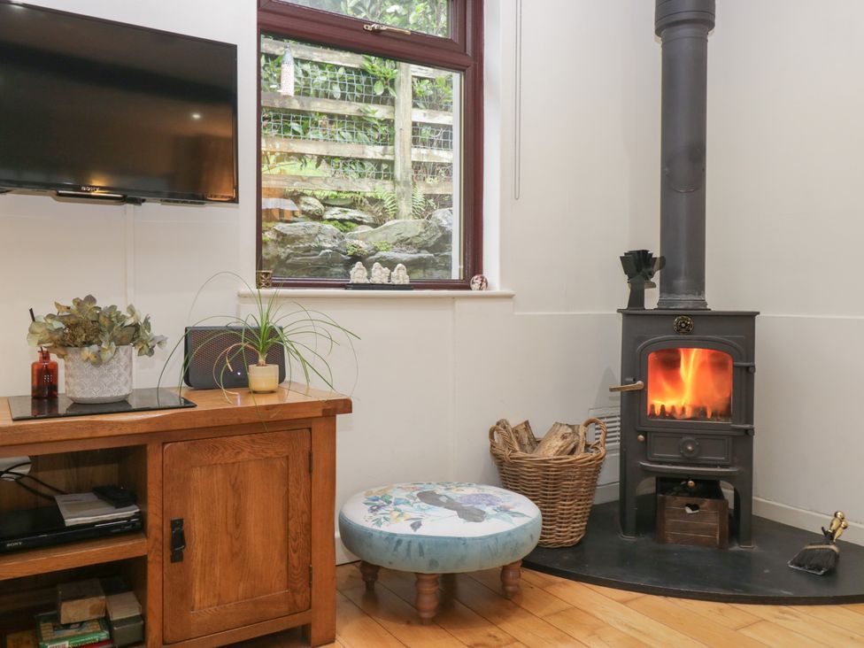 A living room with a wood stove and television at Corner Cottage in Troutbeck