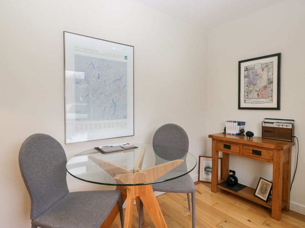 A dining room with a glass table and two chairs at Corner Cottage in Troutbeck